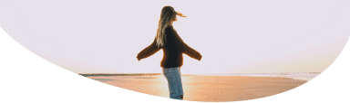 Silhouette Image of a female in the distance wearing a baseball cap, with the sun behind her