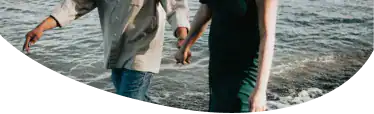 Two people holding hands walking on the sea shore