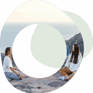 People sitting in a circle on a beach with their arms outstretched