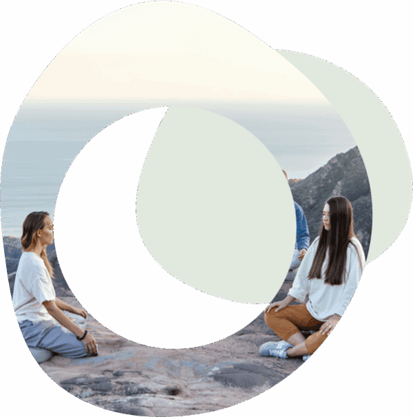 People sitting in a circle on a beach with their arms outstretched