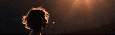 silhouette profile image of a female with sunlight glowing behind her and lighting her hair