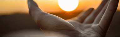 Hand reaching out with sunset in background, symbolizing forgiveness and healing.
